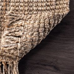 a close up view of a rug on a wooden floor with dark wood in the background