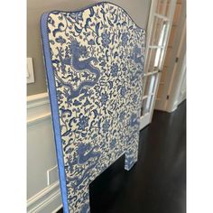 an upholstered headboard with blue and white designs on the top, in front of a doorway