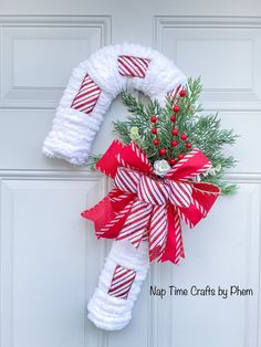 a red and white christmas wreath hanging on a door with candy canes attached to it