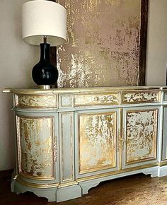 a gold and white cabinet with a lamp on top