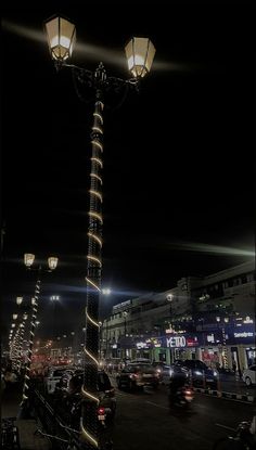 a street light in the middle of a city at night with cars driving by it