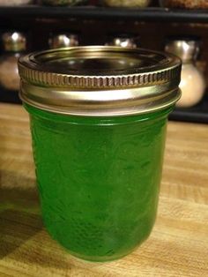 a jar filled with green liquid sitting on top of a wooden table