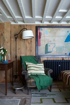 a living room with wood paneling and green chair in front of a radiator