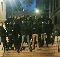 a group of people standing on steps in front of a building at night with their backs turned to the camera