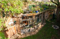 an old building with lots of plants growing on the roof and windows in it's side yard