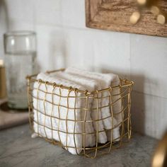 two white towels in a wire basket on a counter