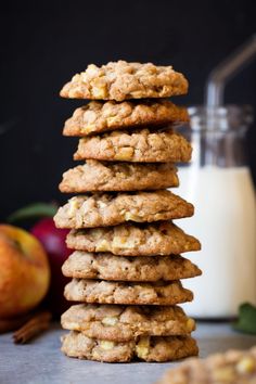 a stack of cookies next to a glass of milk and an apple on the side