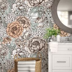 a bathroom with flowers on the wall and a round mirror above it, next to a white sink