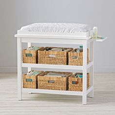 a baby changing table with baskets underneath it