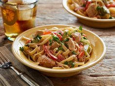 two plates of pasta with meat and veggies next to a glass of tea