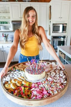 a woman standing in front of a cake with candles on it and lots of sprinkles