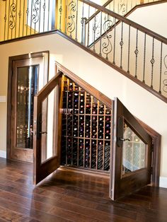 an open wine cellar in the middle of a wooden floored area with stairs and railings