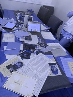 a table covered with papers and laptops on top of blue tables clothed in pictures