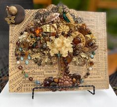 there is a piece of art made out of buttons and beads on top of an old book