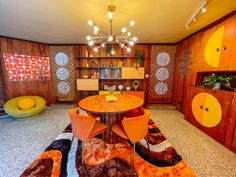 a dining room with orange chairs and a round wooden table in the middle of it