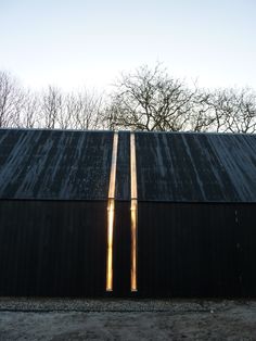 two tall wooden poles sticking out of the side of a black building with trees in the background