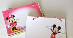 two mickey mouse clipboards on a white table with pink and yellow background, one has a red minnie mouse