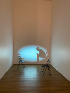 two chairs are sitting in front of a projection on the wall with a man standing next to them