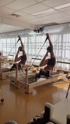 people are doing exercises on rowing machines in a room with windows and blinds behind them