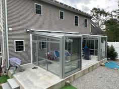 an enclosed patio with chairs on the grass and a back yard in front of a house