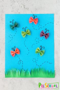 paper butterflies on a blue background with grass