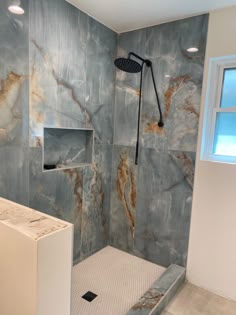 a bathroom with marbled walls and flooring, including a walk - in shower