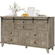 a large dresser with drawers and pictures on it's top shelf next to an orange vase