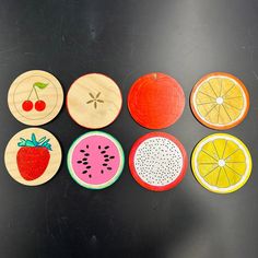 six wooden slices of fruit are arranged on a black surface