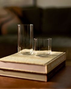 two glasses sitting on top of a book next to each other in front of a couch