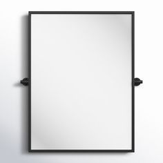 a mirror hanging on the wall with black metal frame and an empty white sheet below it