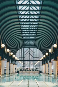 an indoor swimming pool in a large building with lots of windows and lights on the ceiling