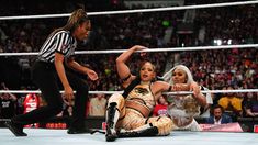 two women in wrestling gear are on the ground and one woman is holding up her hand