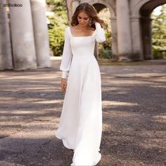 a woman in a white dress is walking down the street with her hand on her head