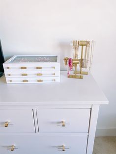 a white dresser with gold handles and drawers