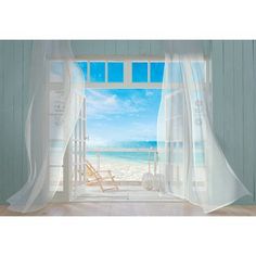 an open window with white curtains and the view of the beach in the distance is shown