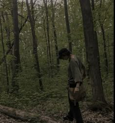 a man standing in the middle of a forest looking at something on his handbag