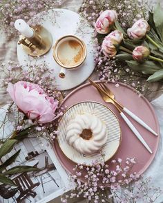 a pink plate topped with a bundt cake next to a cup of coffee and flowers