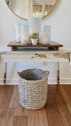 a white table topped with a basket next to a mirror