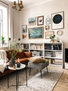 a living room with pictures hanging on the wall and furniture in front of a window