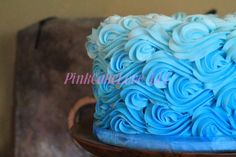 a blue frosted cake sitting on top of a wooden table next to a wall