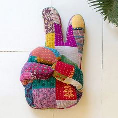 a multicolored patchwork oven mitt hanging on the wall next to a potted plant