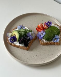 two slices of bread with fruit and flowers on them sitting on a white table top