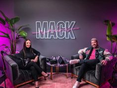 two people sitting on chairs in front of a wall with the word mack painted on it