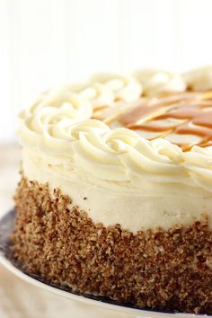 a cake with white frosting and caramel drizzled on top sitting on a plate