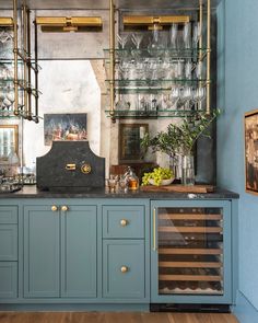 a kitchen with blue cabinets and glassware on the counter top, along with wine glasses