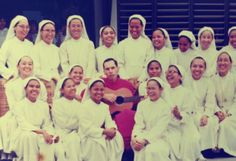 a group of women in white dresses are posing for a photo while holding a guitar