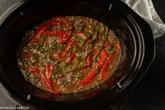 a slow cooker filled with meat and peppers