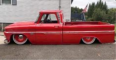 an old red truck parked in front of a house