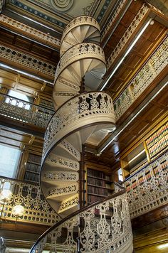 a spiral staircase in the middle of a building with bookshelves on each side