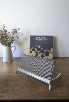 a magazine rack sitting on top of a wooden table next to a vase with flowers